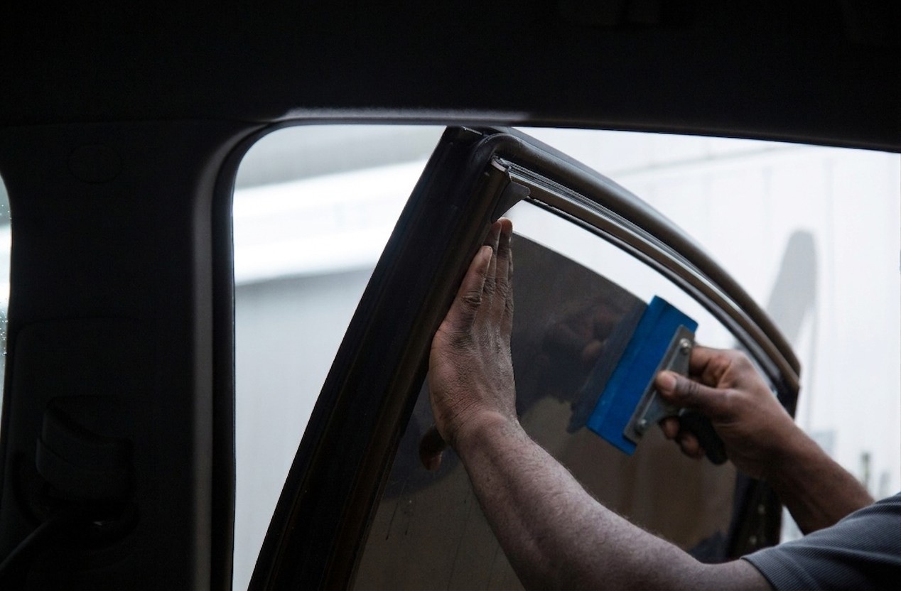 PureTint installer squeegeeing window tint film onto a car side window